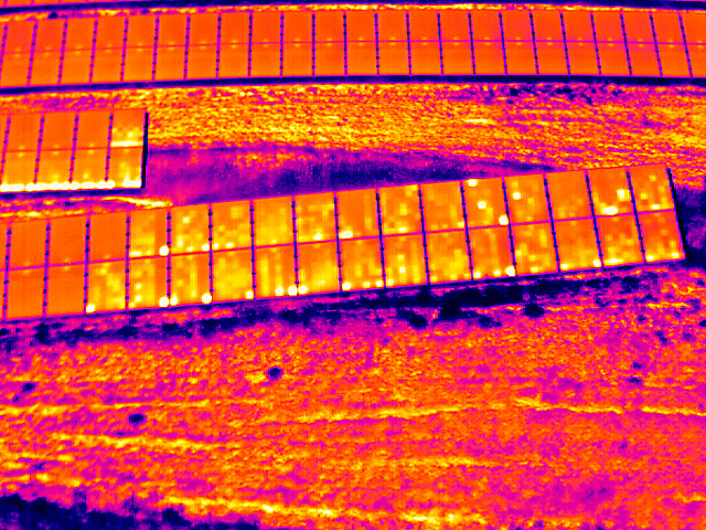 Thermografische Drohnenaufnahme einer Photovoltaikanlage mit punktuellen Hotspots innerhalb einzelner Modulzellen