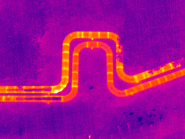 Thermisch auffällige oberirdische Fernwärmeleitung in einer Drohnenaufnahme mit Wärmebildkamera